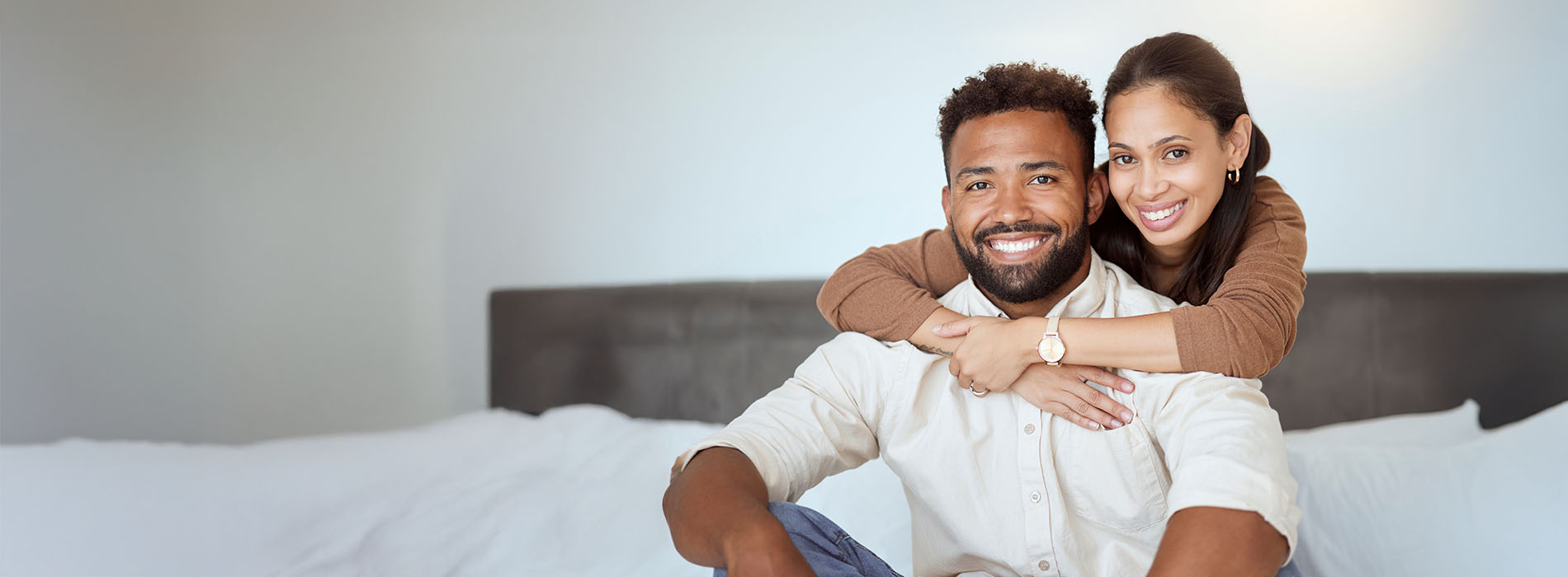A man and woman are embracing each other with smiles on their faces they appear to be posing for a photograph, likely a family portrait.
